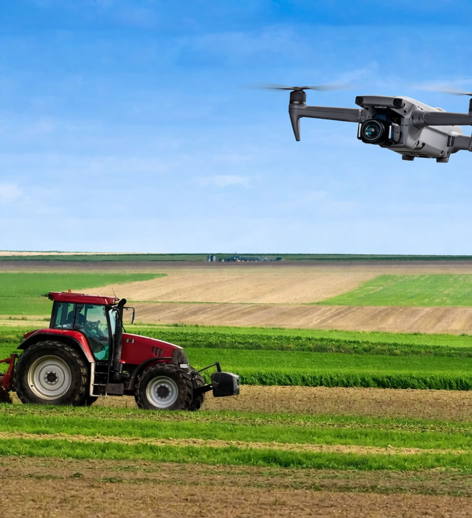 Tracteur rouge labourant un champ avec un drone volant au-dessus, ciel bleu en arrière-plan.